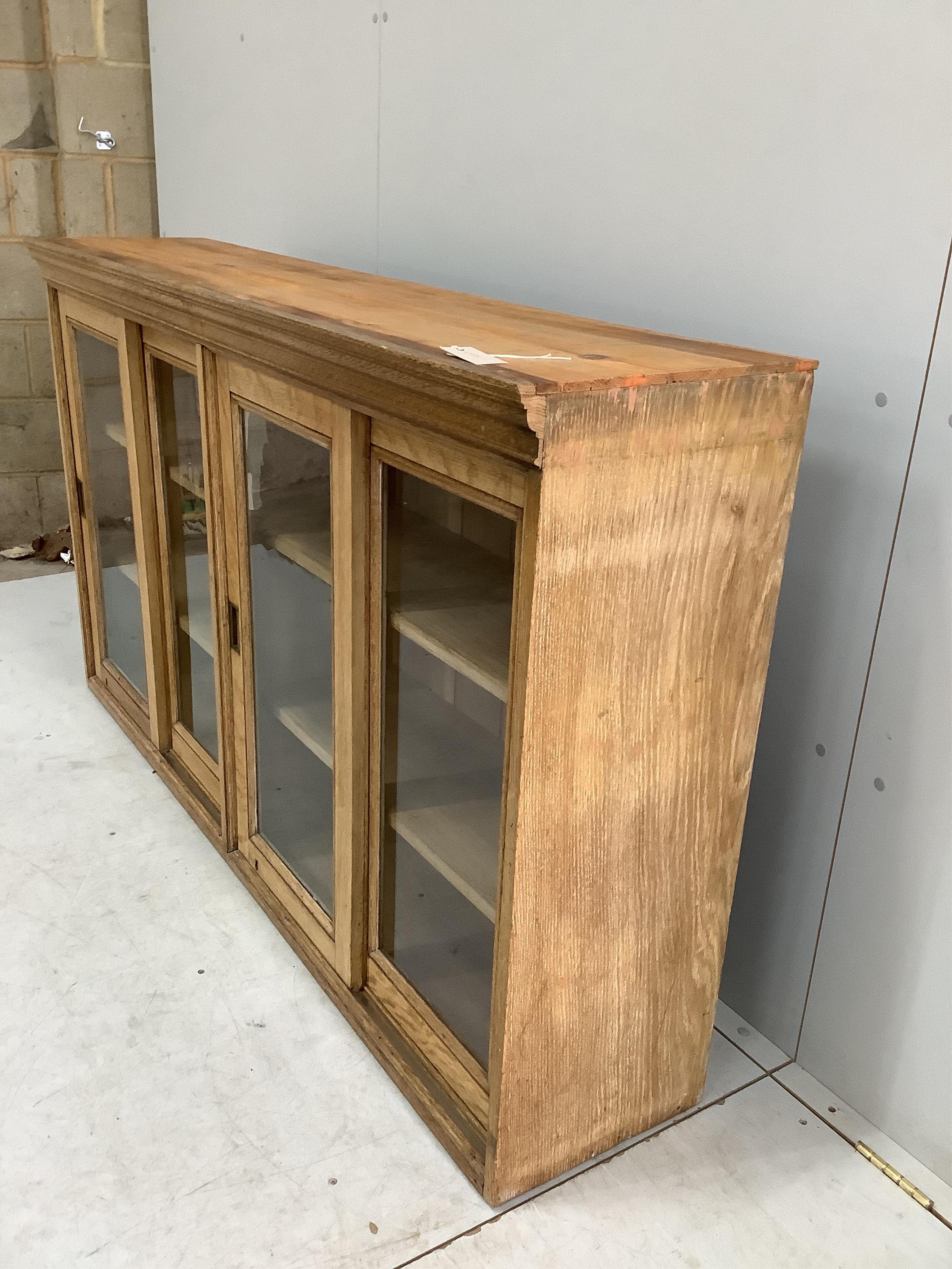 An early 20th century oak bookcase enclosed by sliding doors, width 164cm, depth 36cm, height 96cm, adapted. Condition - fair